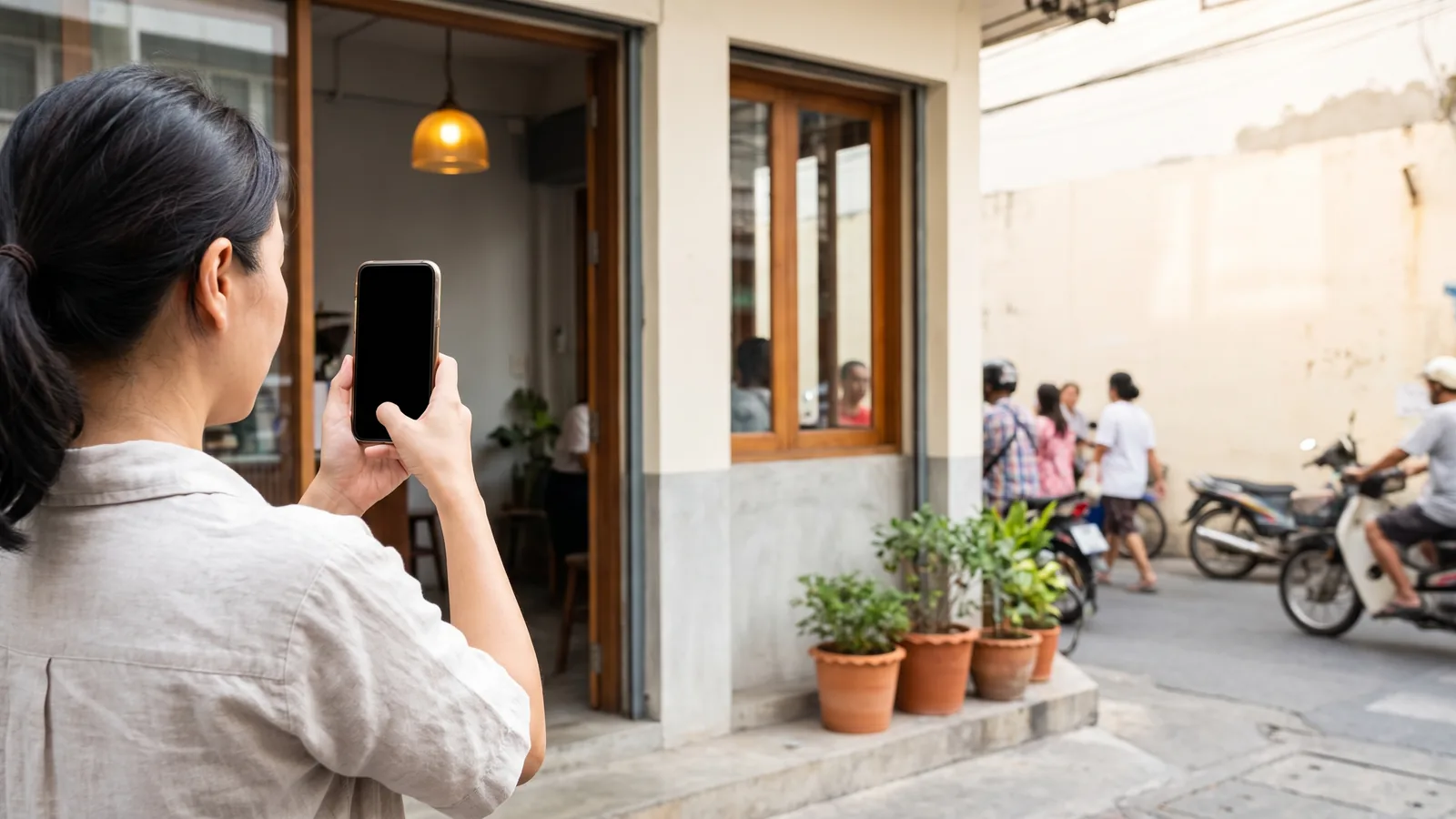 เจ้าของร้านยกมือถือขึ้นถ่ายรูปหน้าร้านของตัวเอง